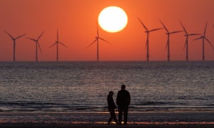 The sun sets behind the wind turbines of Burbo Bank Offshore Wind Farm in the Irish Sea.