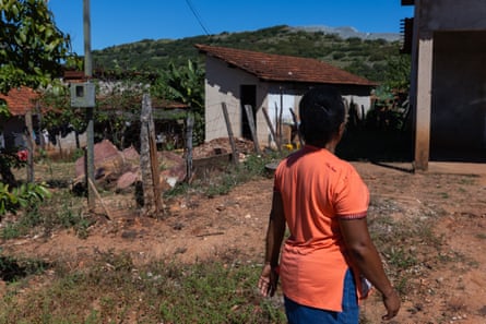 A woman looks over her shoulder towards some buildings with a hill behind them.