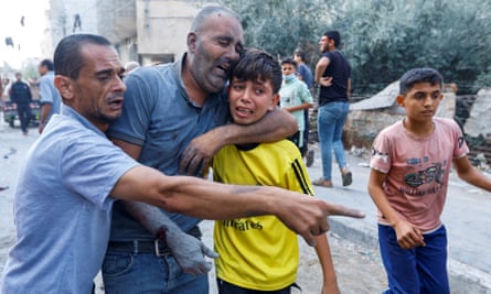 شاب فلسطيني أصيب في غارات إسرائيلية على منازل، يحتضن طفلا في رفح، جنوب قطاع غزة.