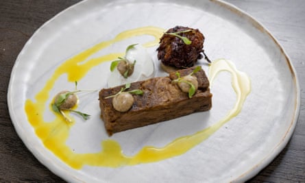 A rectangle of curried herdwick lamb with a bhaji and a yellow drizzle on a round white plate