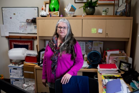 Woman wearing a purple sweater and scarf stands in office.