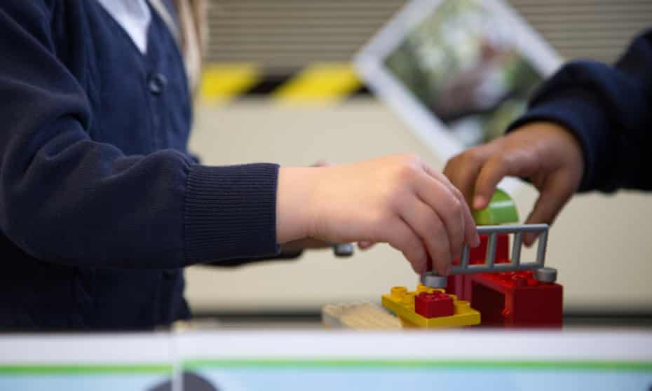 UK primary school children play with lego in a classroom
