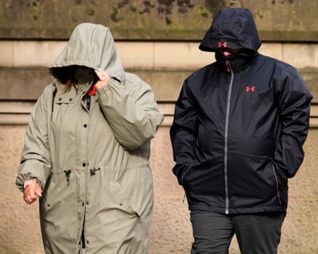 Two people in hooded jackets walk side by side, their faces obscured by pulled-up hoods