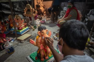 An artist paints a statue of Lord Ganesh.