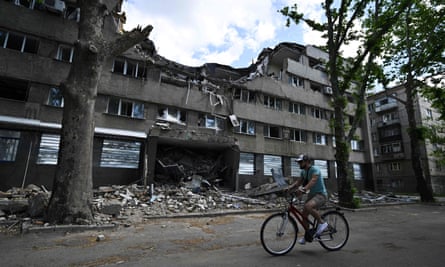 A man cycles past a building of hotel Ingul n the southern Ukrainian city of Mykolaiv, destroyed by a Russian airstrike in March.