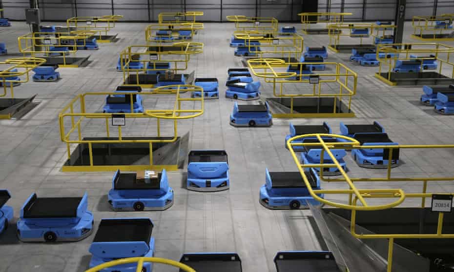 Amazon robots transport packages from workers to chutes at an Amazon warehouse in Goodyear, Arizona, 2019