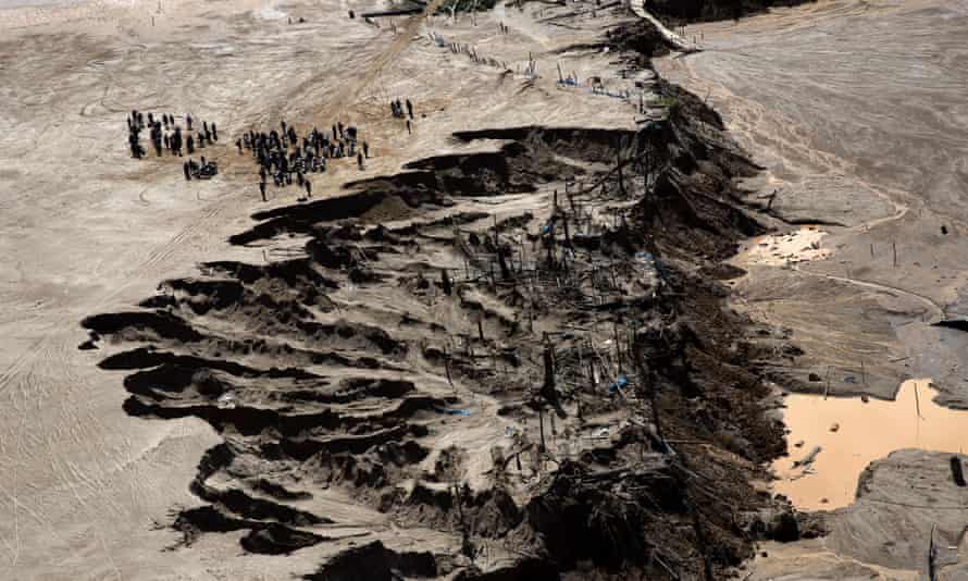 Police stand next to a crater created by gold miners during a police operation to eradicate illegal mining in an area known as La Pampa, in Peru’s Madre de Dios region, in August 2015. Peruvian security forces blew up more than one hundred gasoline engines used to extract gold from the sandy soil.