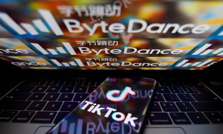 TikTok logo on a smartphone with a ByteDance logo on a laptop in the background.
