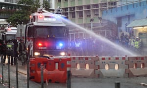 An anti-riot police vehicle equipped with water cannon clears a barricade from the road