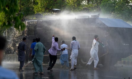 Supporters of Imran Khan throw stones at a water cannon in Lahore.