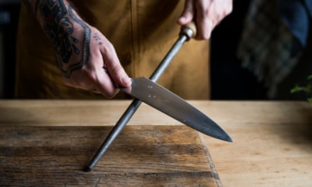 Professional chef sharpening knife in the kitchen