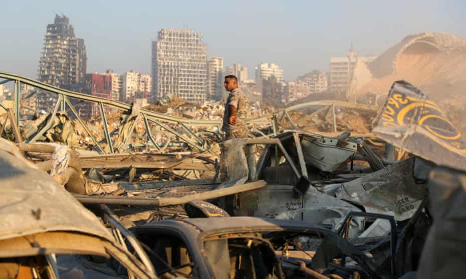 Man stands amid rubble and wrecked vehicles at the Port of Beirut