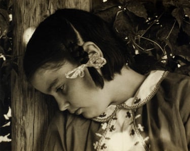 Miss Thomson rests her head against a wooden post, eyes downcast, amid leaves