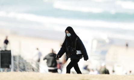 A woman wears a face mask at Bondi Beach in Sydney. People in the city have been strongly encouraged to wear masks.