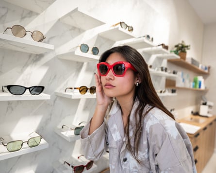 Young woman trying on red sunglasses in an opticians