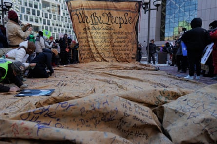 People sign a large copy of the Declaration of Independence unfurling on the ground