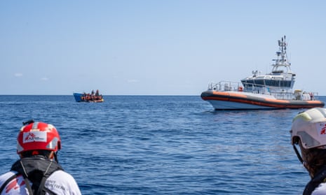 MSF volunteers look on at large Libyan coastguard ship and two smaller vessels
