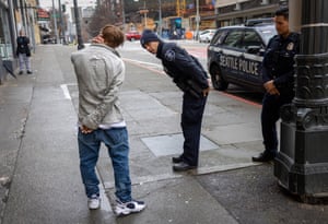 Police officers check on a man who said he has been smoking fentanyl in downtown Seattle