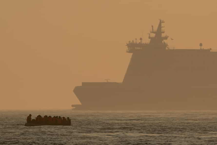 An inflatable craft carrying migrant men, women and children crosses the shipping lane in the English Channel off the coast of Dover