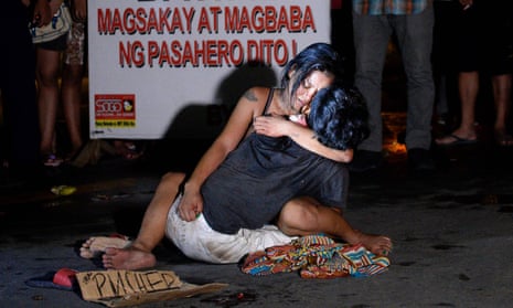 A dead Manila rickshaw driver, Michael Siaron, is embraced by his partner