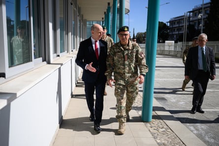 John Healey, wearing a suit and tie, walks alongside a military officer in full uniform