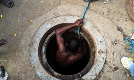 A worker comes out from an underground sewage chamber after cleaning.