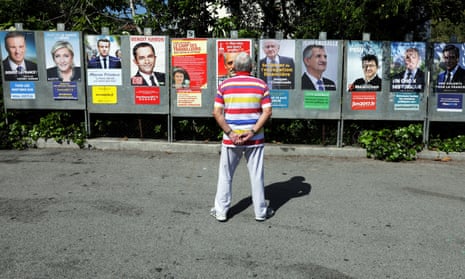 A man looks at campaign posters of the candidates running in the 2017 French presidential election.