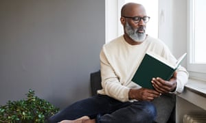 Mature man sitting at window, reading a book