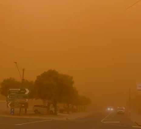 A town is covered in an orange cloud of dust during a storm.