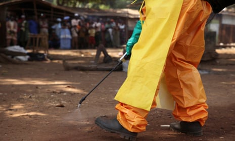 A member of the French Red Cross disinfects the area around a motionless person suspected of carrying the Ebola virus.