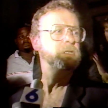 man with beard wearing glasses witha. microphone in front of him
