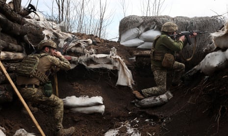Ukrainian soldiers shoot with assault rifles in a trench on the front line with Russian troops in Luhansk region on April 11, 2022.