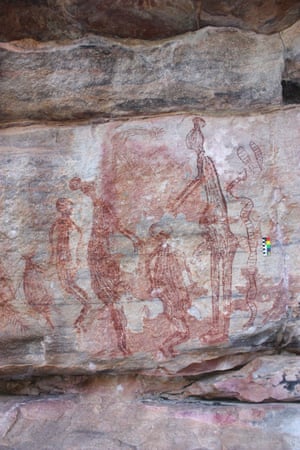 A painting from Namunidjbuk shows two male Maliwawas with ball headdresses reaching down to a shorter human figure with a snake behind the male on the right and behind the left male a female and a macropod. A human figure with a cone and feather headdress is above.