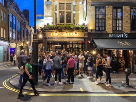 London nightlife drinkers on pavement outside popular traditional pub in SohoPeople drinking outside a traditional pub in the heart of London at night.