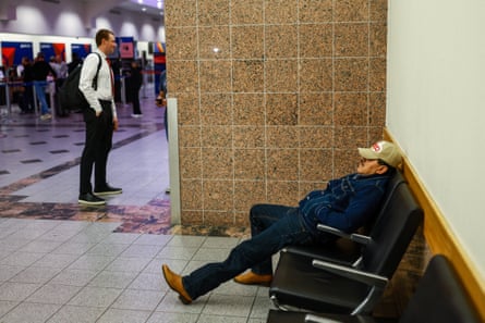 Man in baseball cap rests on chair at airport