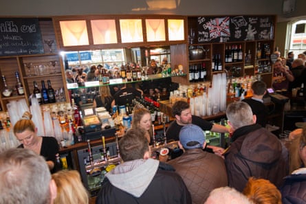 People queue up along a busy bar hoping to get served