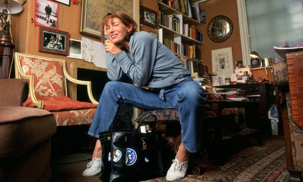 Birkin wearing jeans in cheerfully cluttered study, bookcase and desk in background