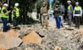 A Lebanese soldier and emergency responders survey an impact crater after an Israeli airstrike hit a road in the southern village of Alma al-Shaab