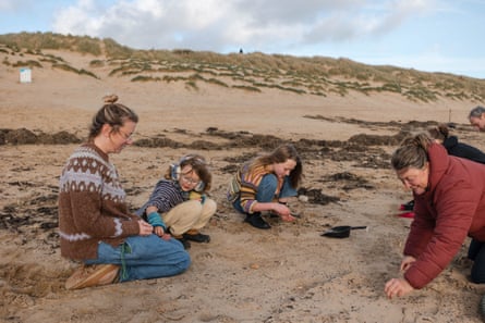 A family helps to clean up biobeads on Camber Sands.