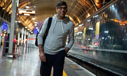 Sunak wearing hoodie and rucksack getting off a train in London