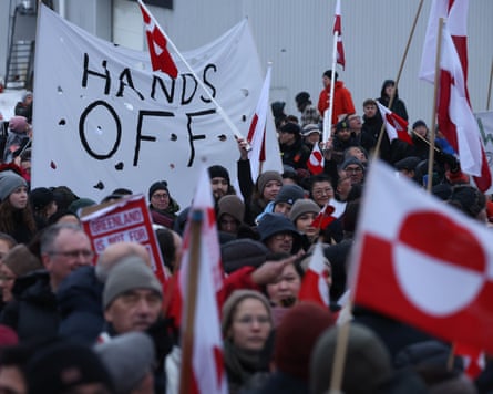 People carry Greenlandic flags and a banner that reads ‘Hand Off’ as they take part in a protest in Nuuk against Donald Trump’s threats to seize Greenland.