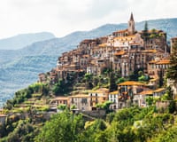 A picture of the village with red roofs, a church at its apex and hills behind