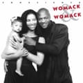 the Womacks, smiling, with her holding a baby with a bow in her hair
