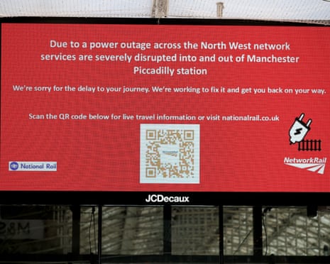 A red digital sign displays a power outage message and QR code inside Manchester Piccadilly station