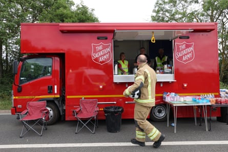 Red Salvation Army food lorry, male emergency services worker walks past