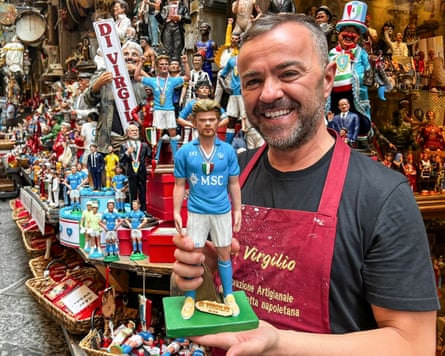 The artist Genny Di Virgilio poses with a terracotta figurine depicting Kevin De Bruyne in Naples' Via San Gregorio Armeno