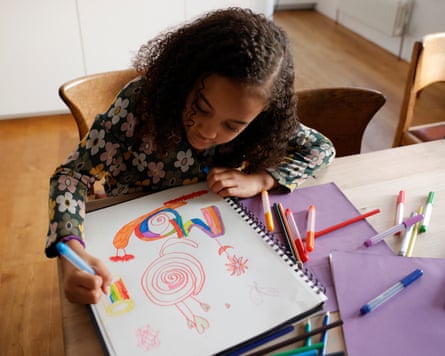 young girl drawing pictures at a table