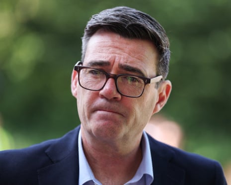 Andy Burnham in dark-framed glasses and a dark suit looks directly ahead with a serious expression
