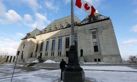 A worker raises a Canadian flag in front of the Supreme Court building in Ottawa