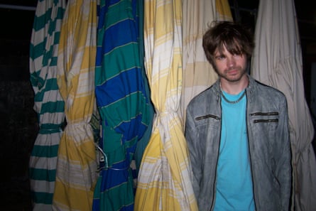 A man standing next to folded-up parasols.